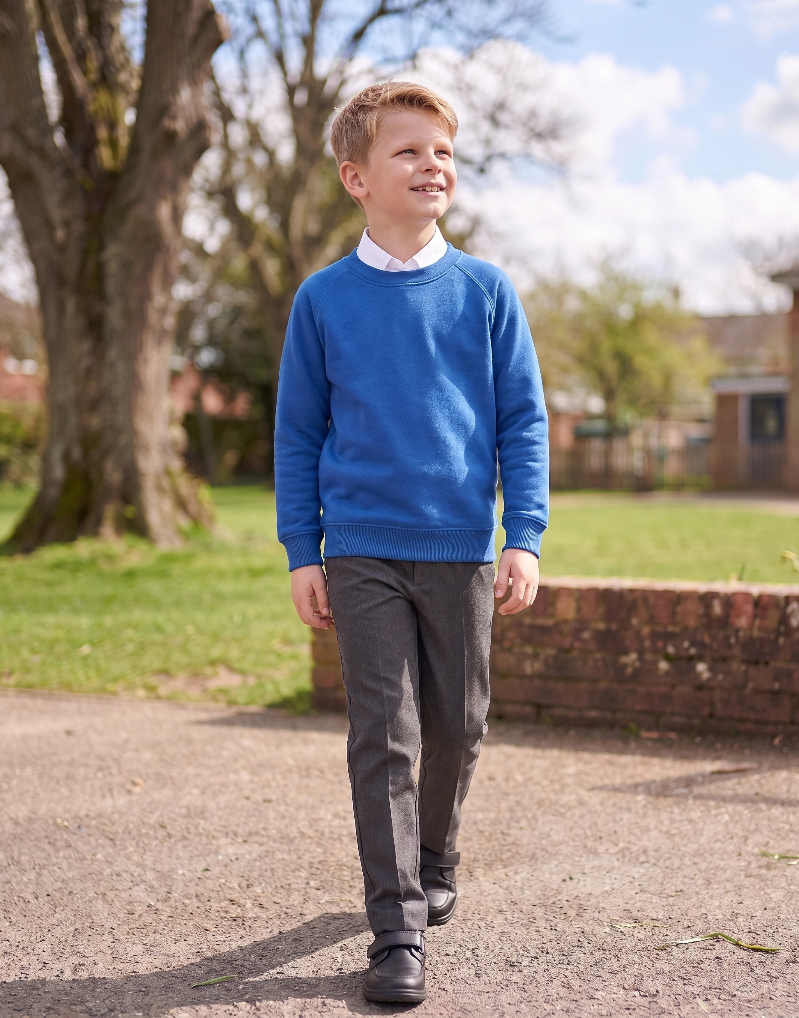 Child wearing a royal blue organic cotton school sweatshirt with a classic crew neck, front view.