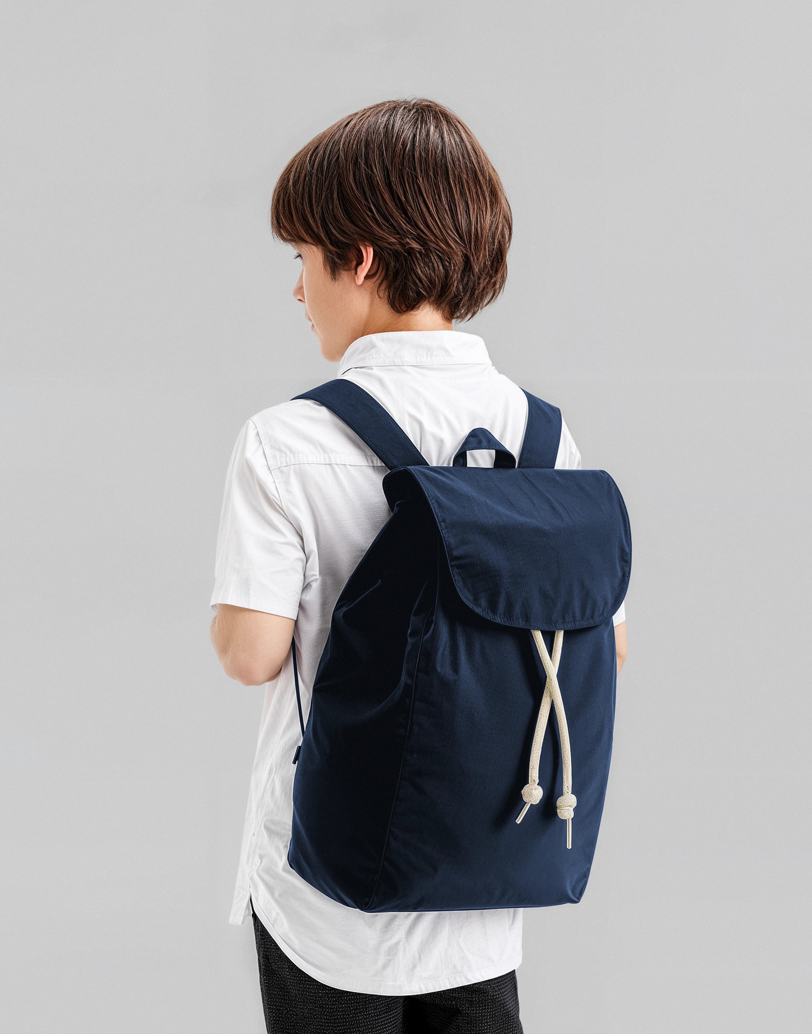 A boy wearing a navy  backpack made from 100% organic cotton 