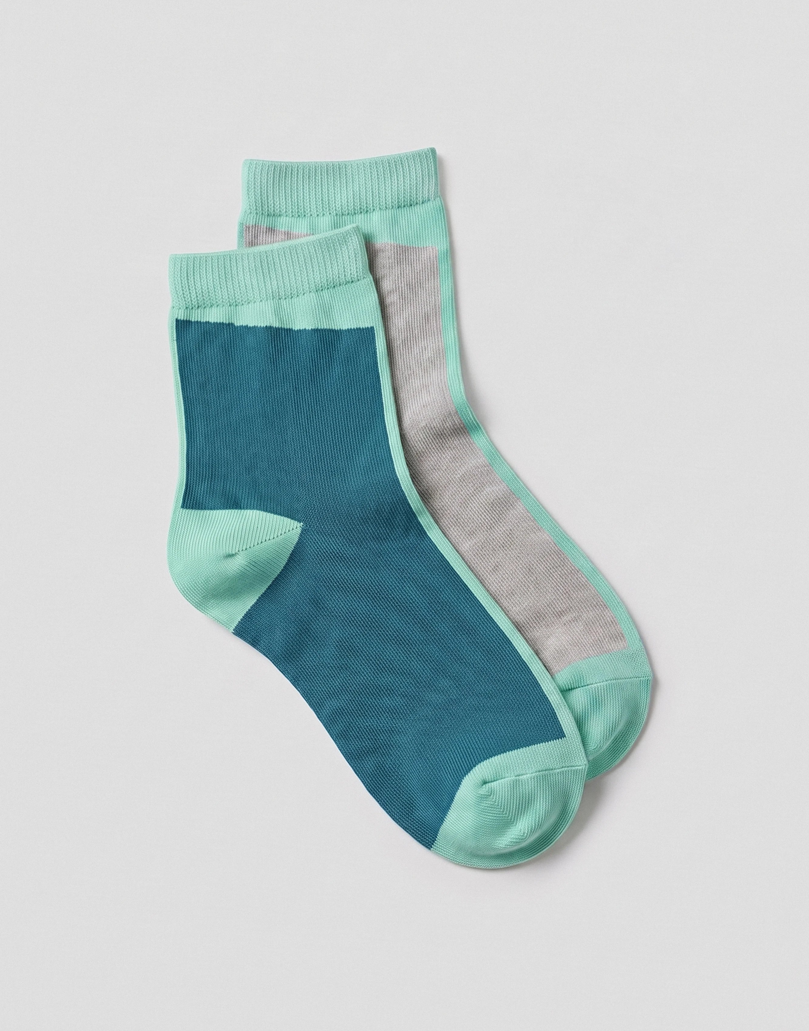 A pair of ankle socks in a color-blocked design featuring teal blue, mint green, and light gray panels, displayed on a light gray background.