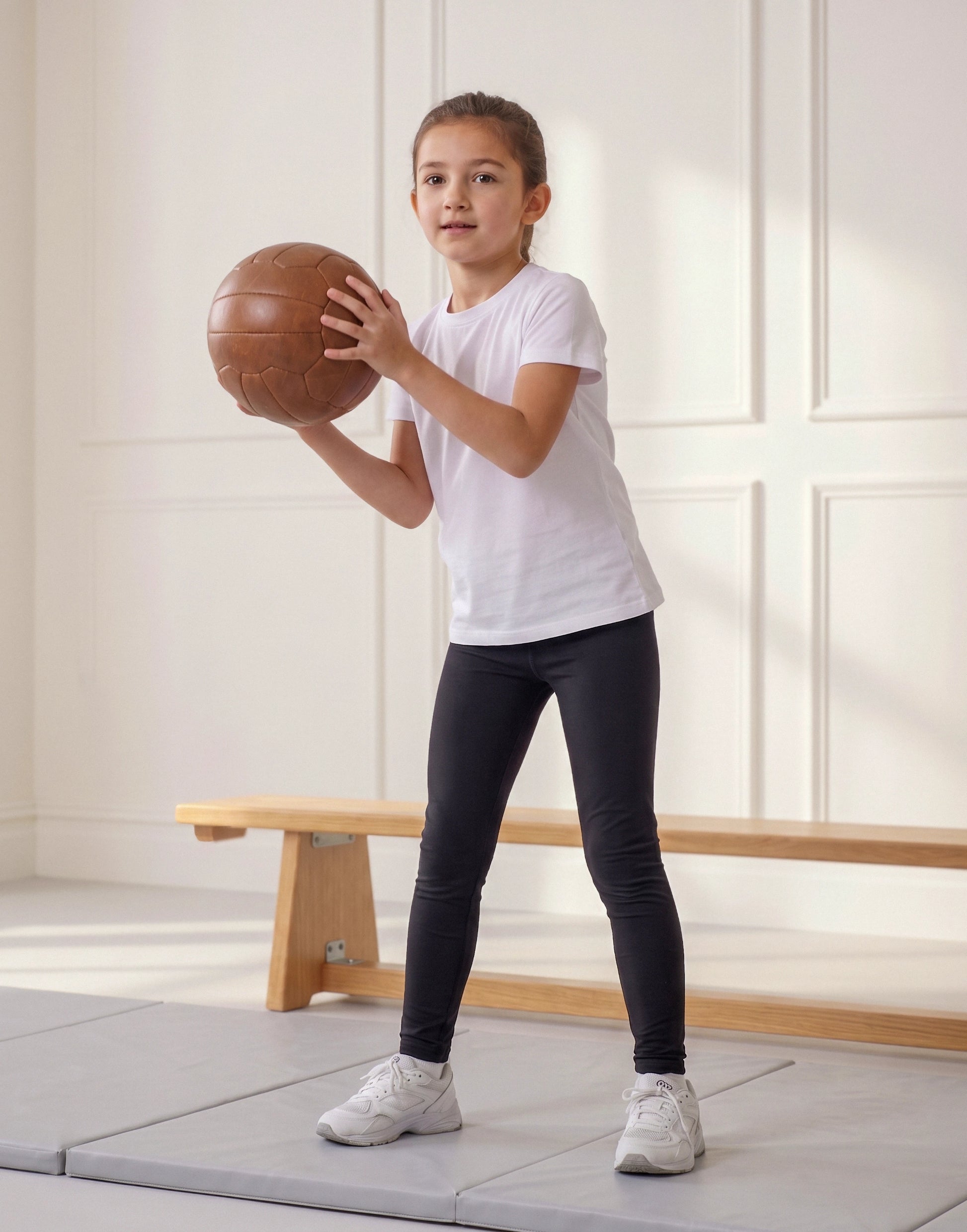 Girl wearing black jersey leggings made from 100% GOTS-certified organic cotton, front view.