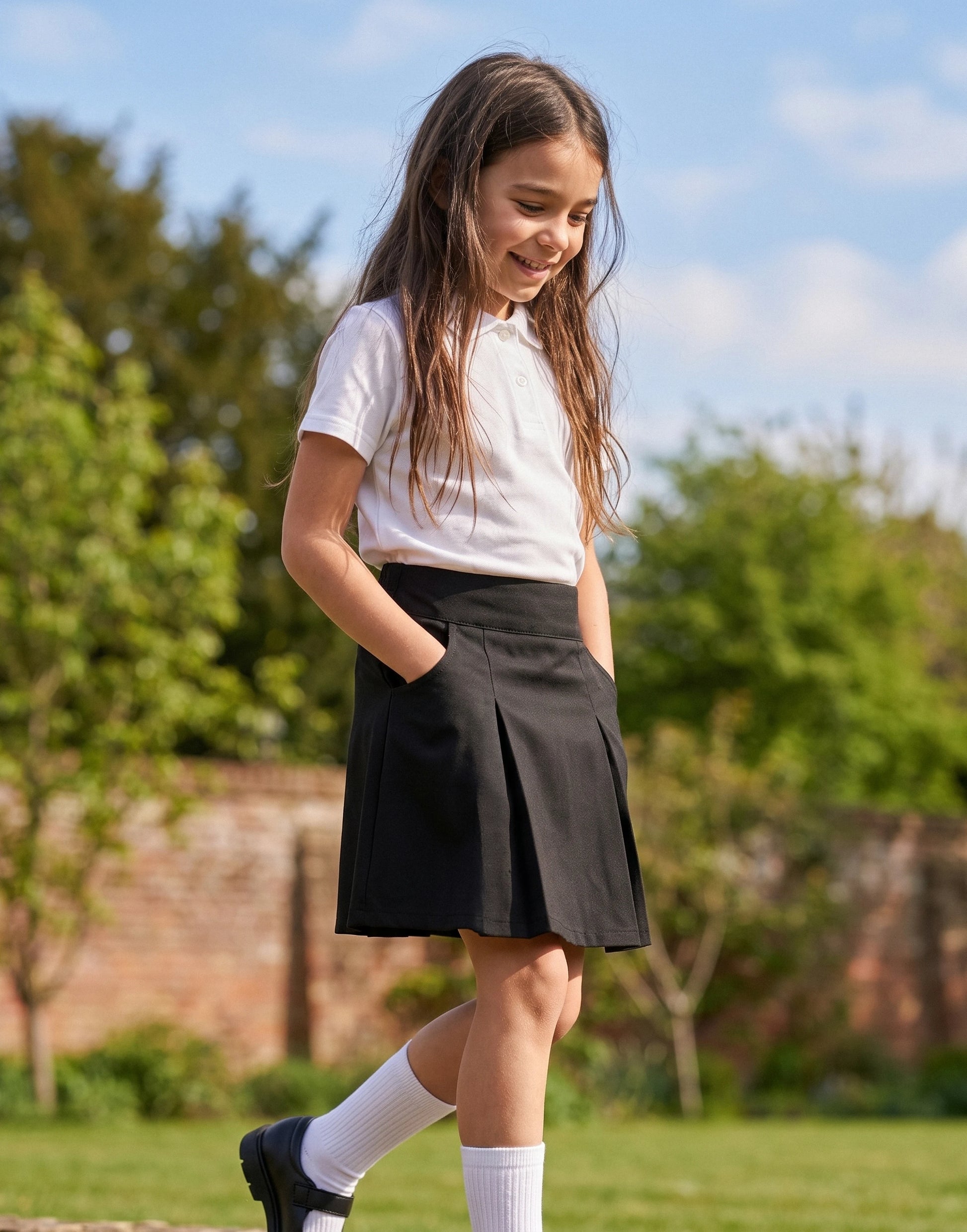 Girl wearing a black pleated school skirt made from 100% GOTS-certified organic cotton, front view.