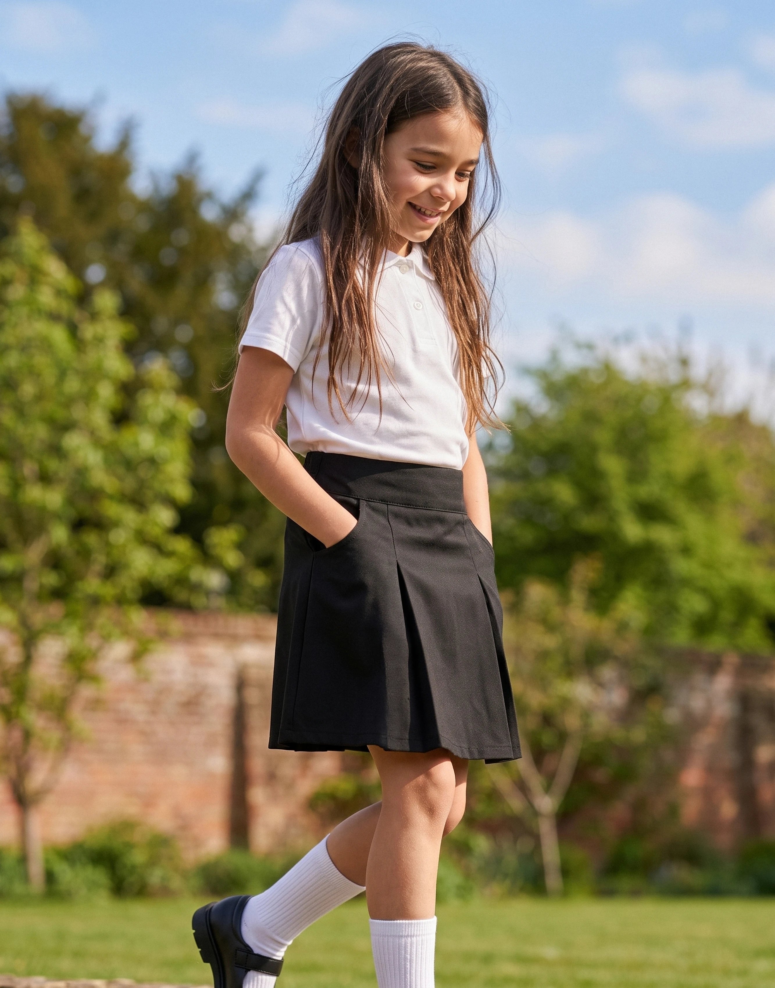 Girl wearing a black pleated school skirt made from 100% GOTS-certified organic cotton, front view.
