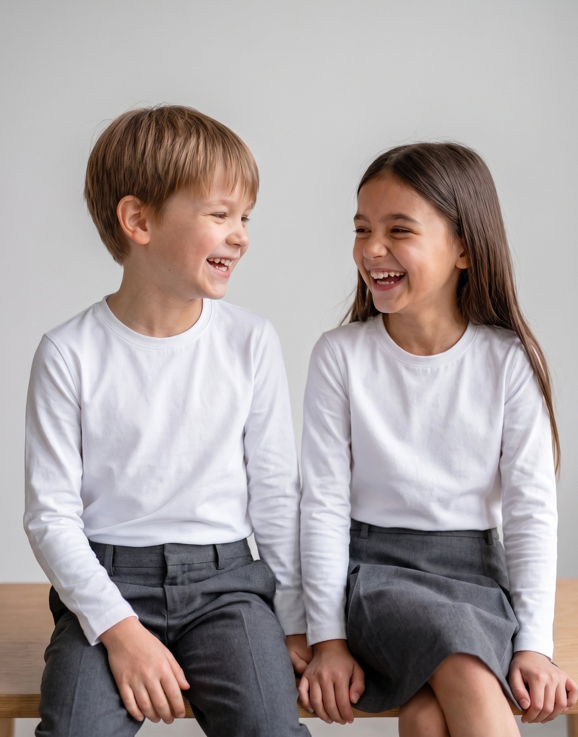 Children wearing a white long sleeve T-shirt made from 100% GOTS-certified organic cotton, front view.