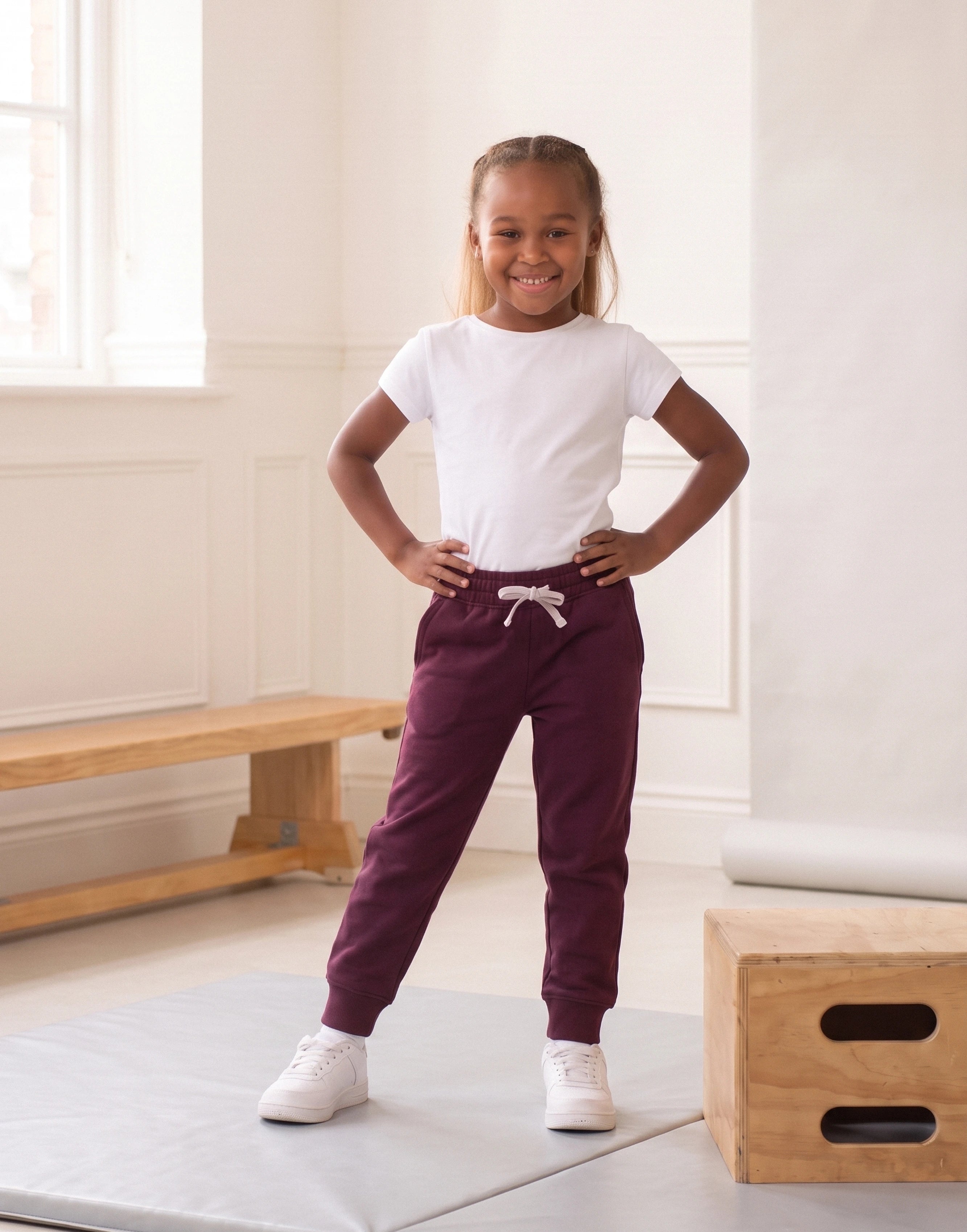 Girl wearing maroon organic cotton joggers, front view