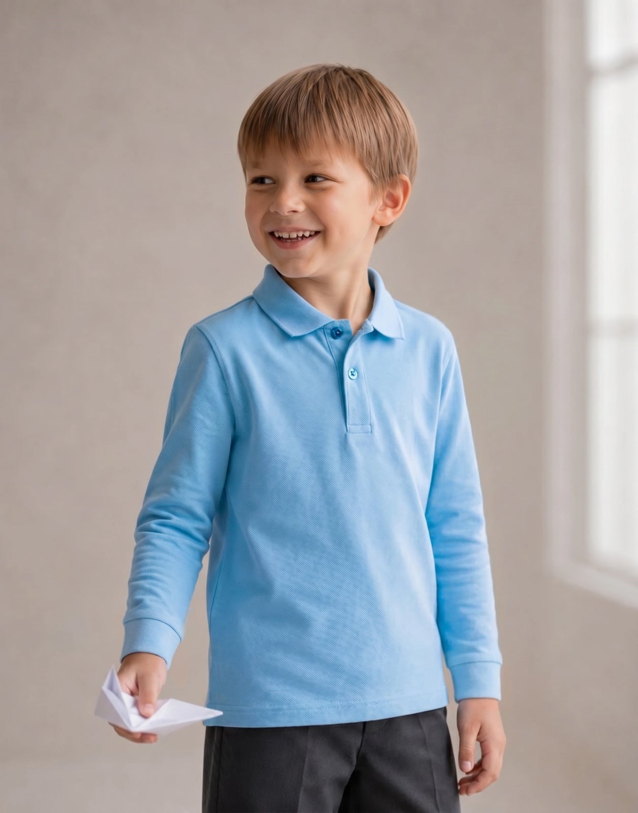 Boy wearing a sky blue organic cotton long sleeve school polo shirt.