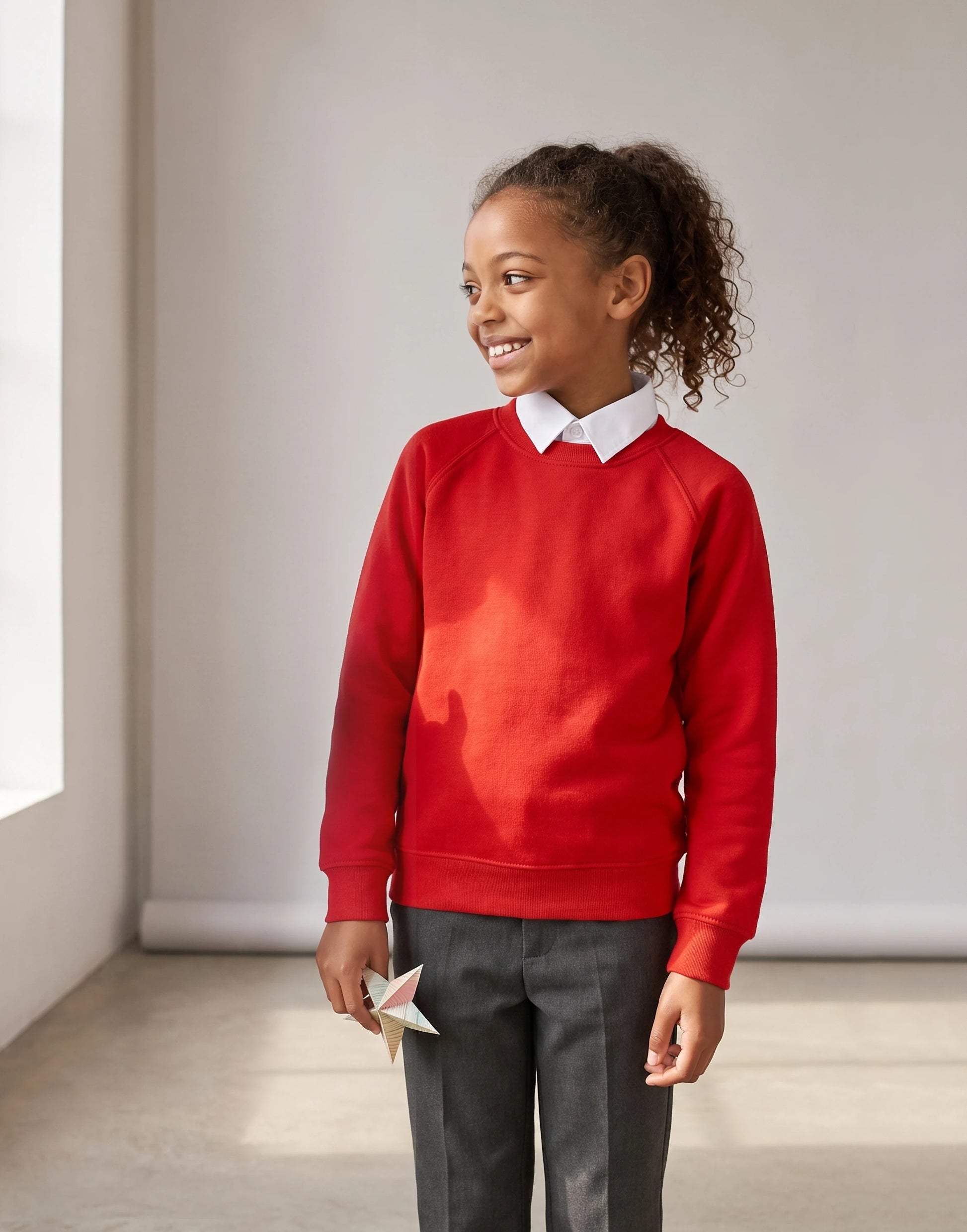 Child wearing a red organic cotton school sweatshirt with a classic crew neck, front view.