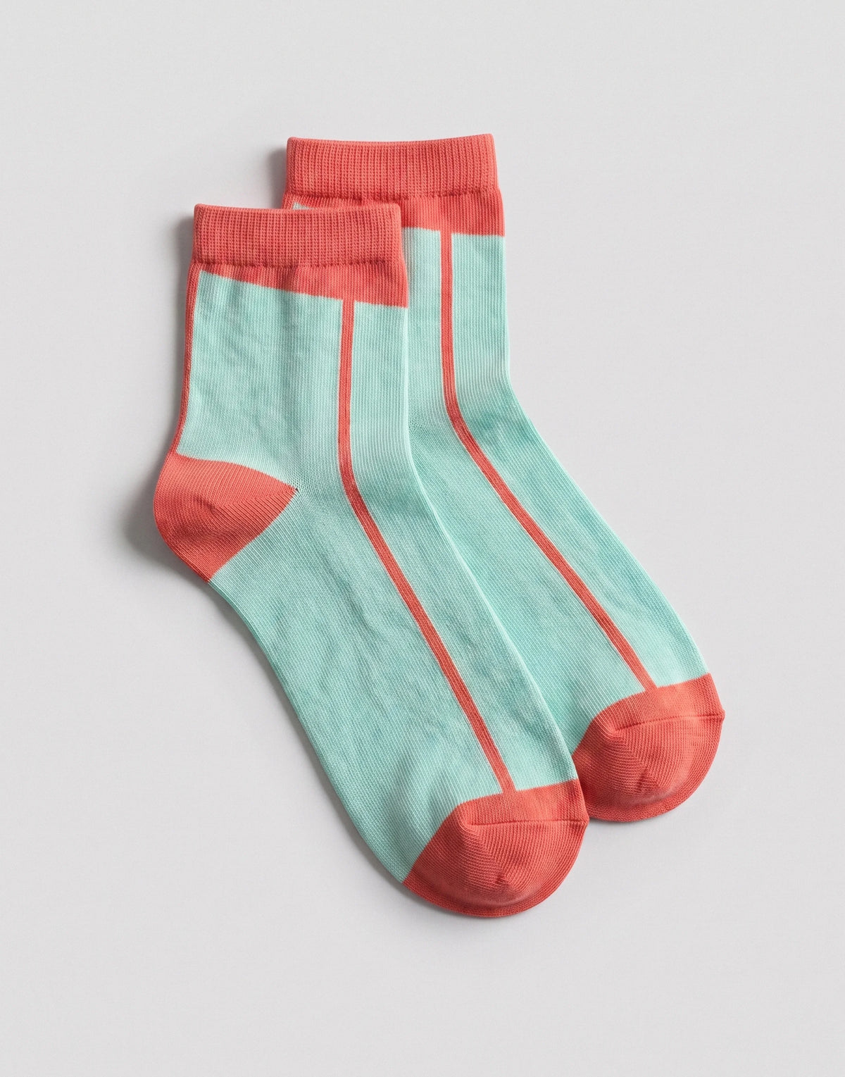 A pair of ankle socks in mint green with coral pink accents on the cuffs, heels, and toes, laid flat on a light gray background.