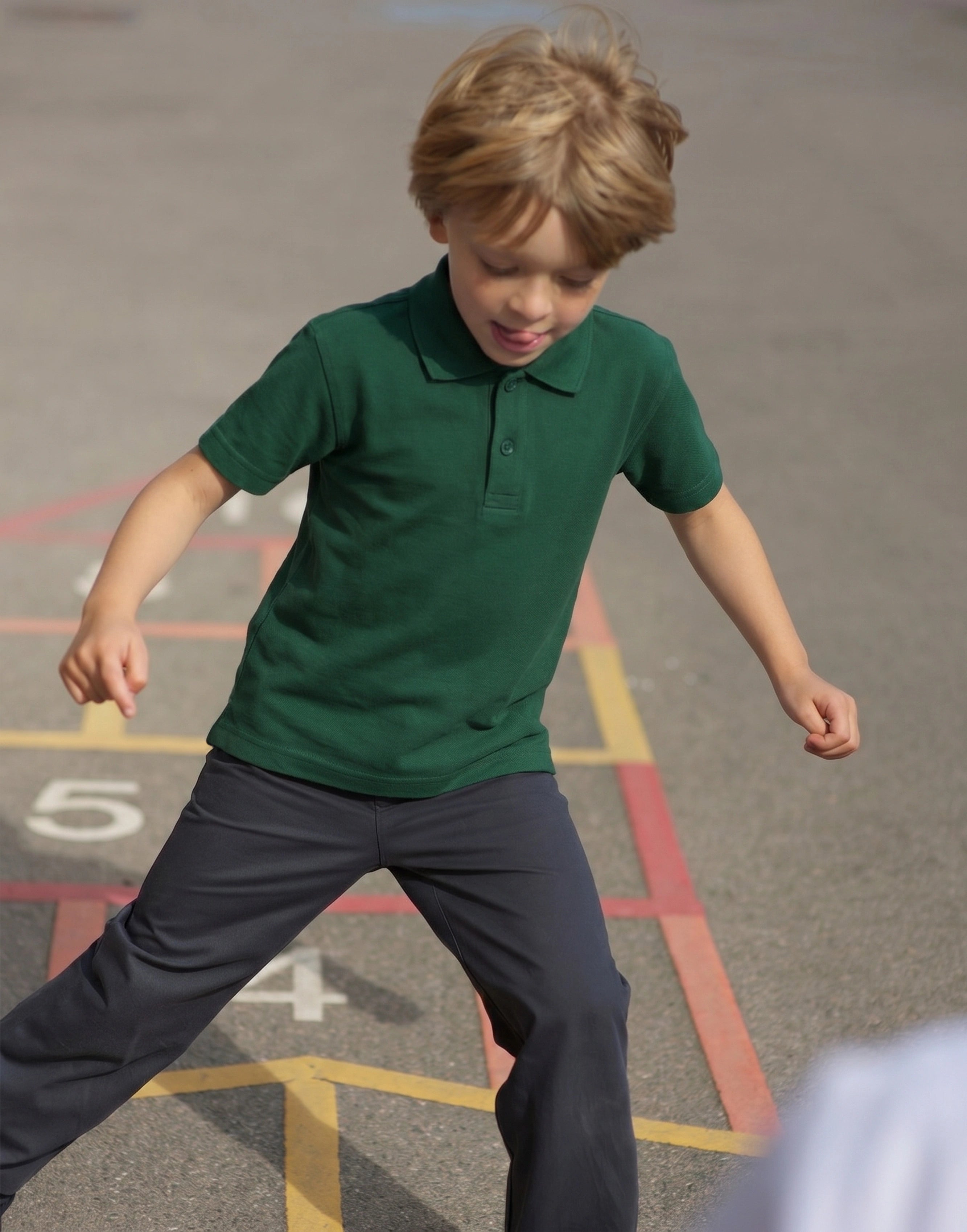 Child wearing a bottle green short sleeve school polo shirt made from 100% organic cotton, front view.