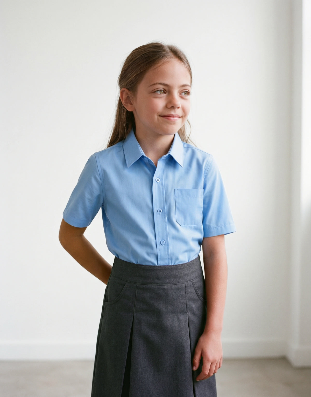 Child wearing a blue slim fit short sleeve school shirt made from 100% organic cotton, front view.