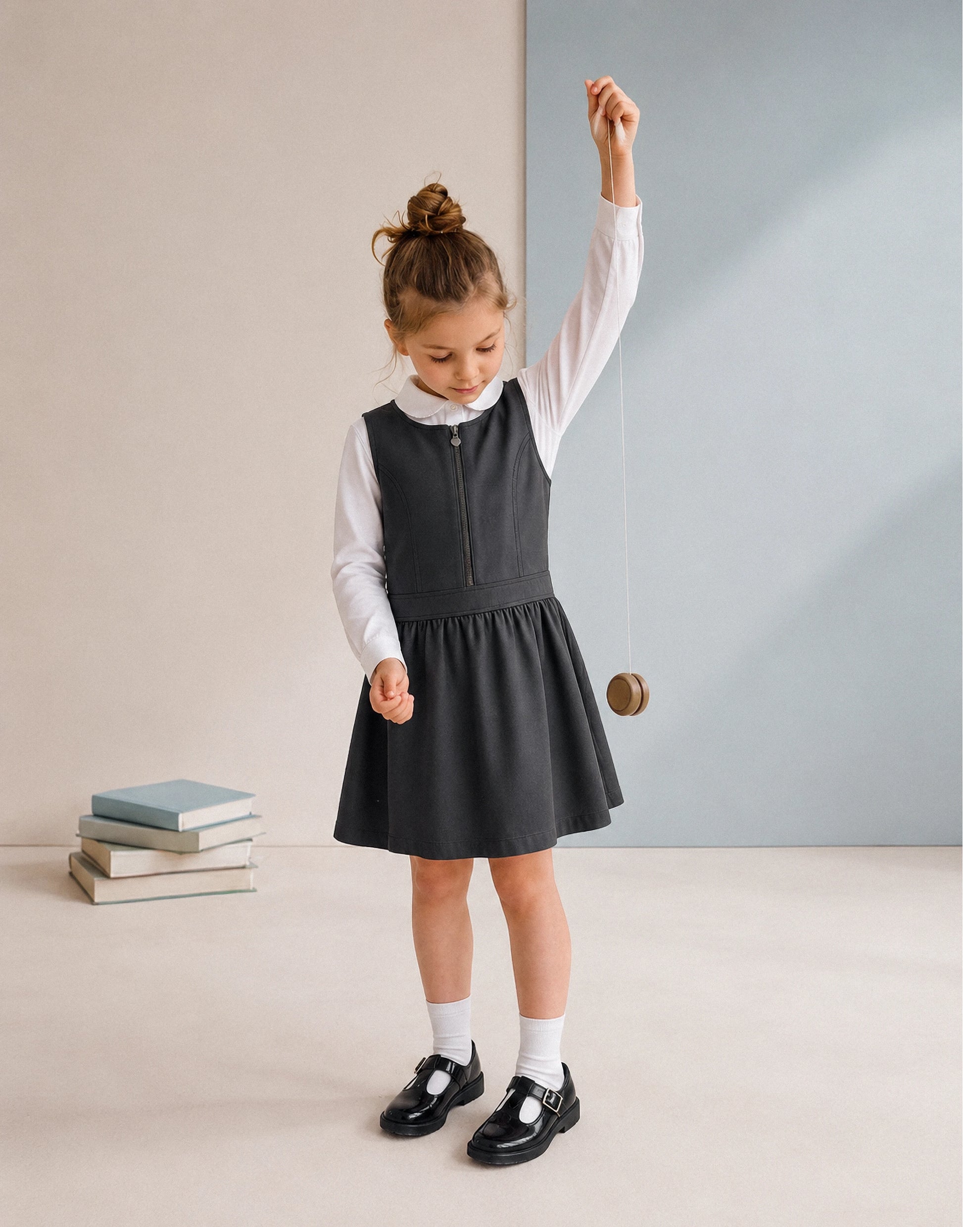 Girl wearing a grey zip front school pinafore made from 100% GOTS-certified organic cotton, front view.